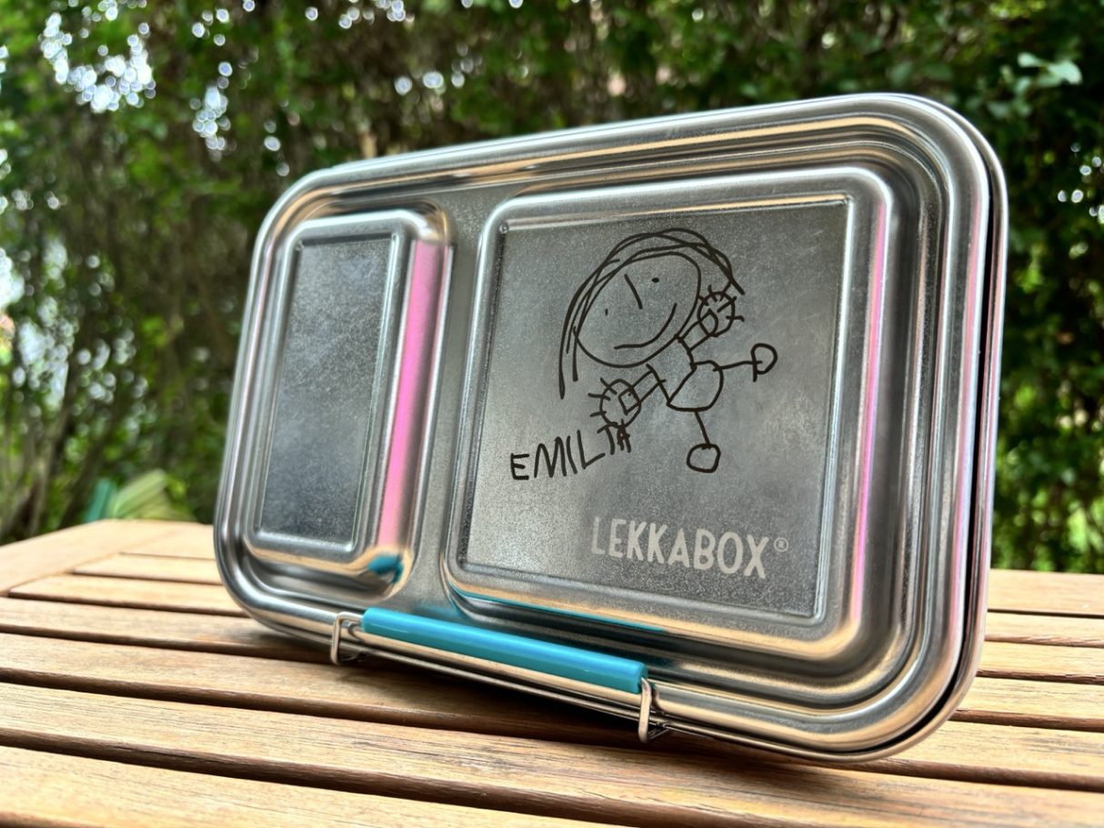 Edelstahlplatte mit eingeätztem Cartoon-Motiv und buntem Stift-Clip.