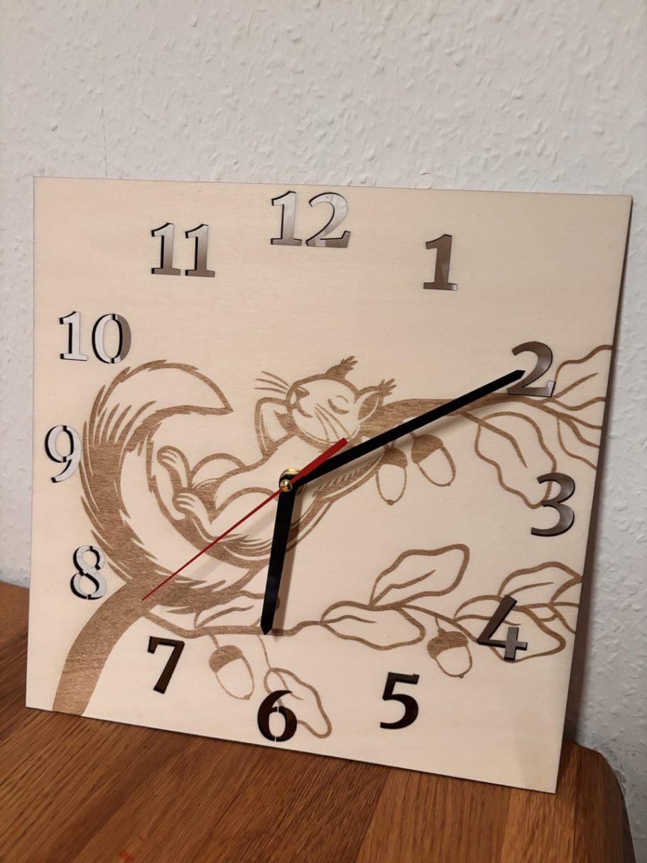 Holzuhr mit einem schlafenden Tier auf einem Ast und klassischen Ziffern.