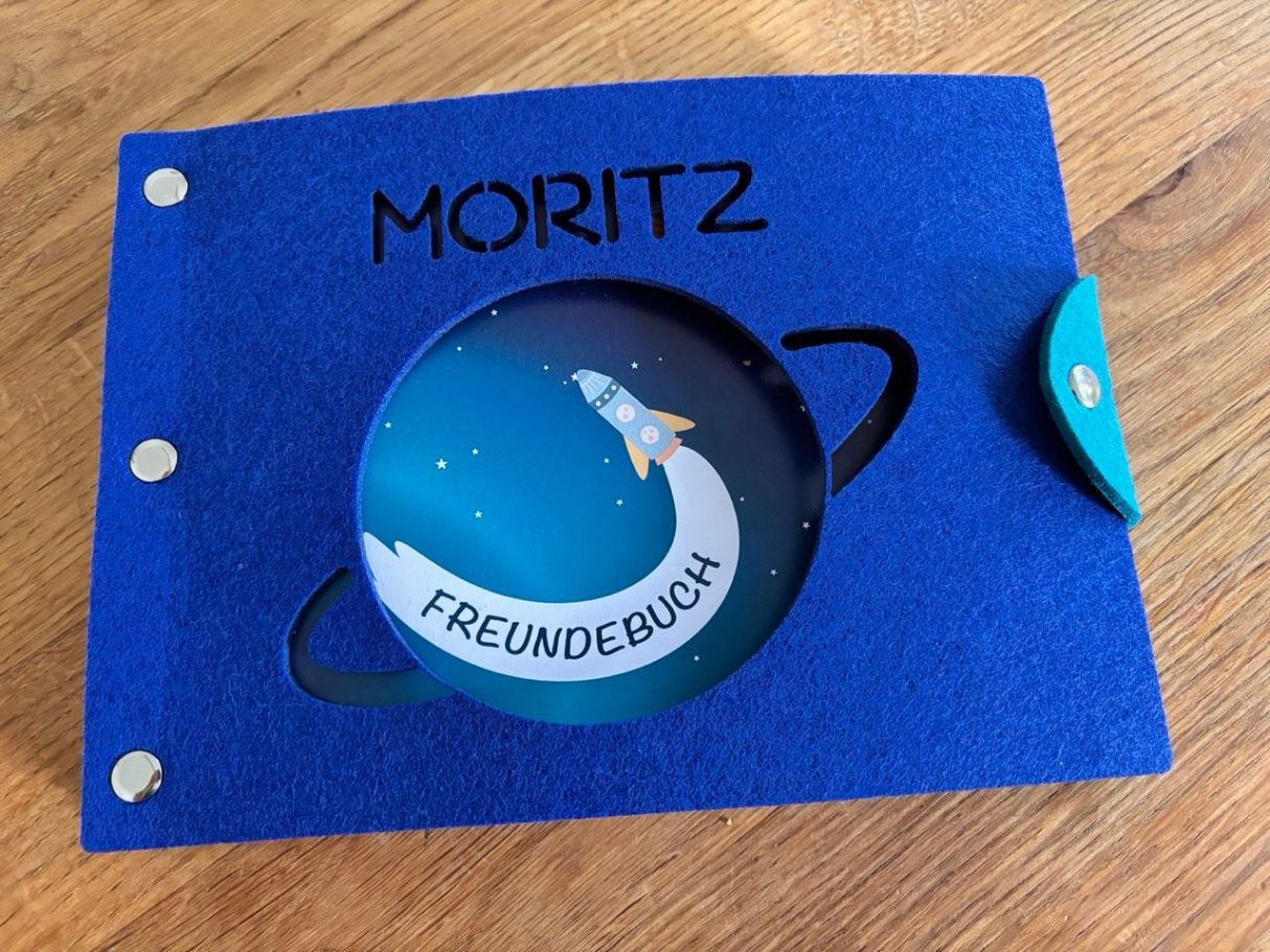 Blaues Album mit dem Namen „Moritz“ und einem Motiv von einer Rakete im Weltall.