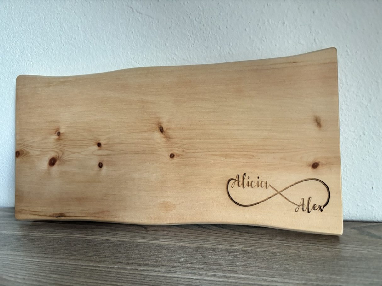 Holzbrett mit geschwungener Form und eingravierter Unendlichkeitsschleife.