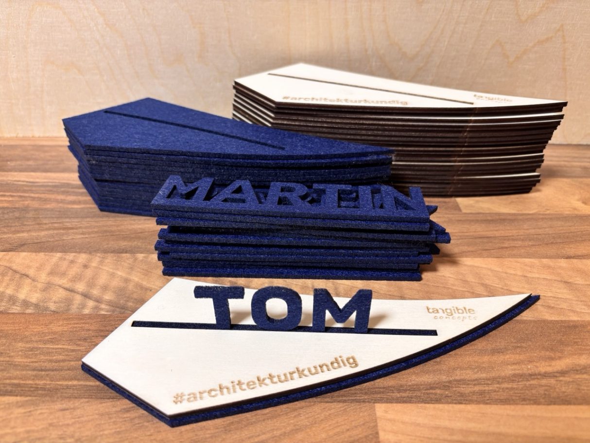 Bunte Namensschilder aus Holz, mit den Namen "MARTIN" und "TOM" in verschiedenen Schriftarten.