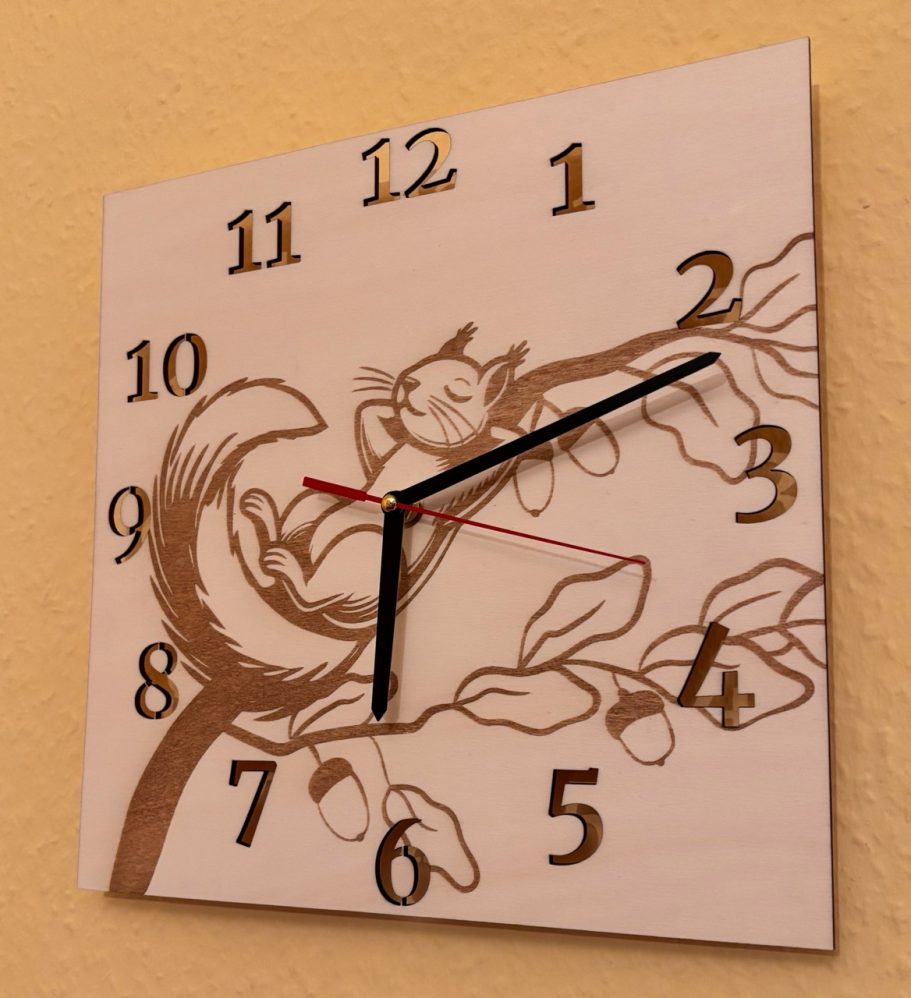 Wanduhr mit einem grafischen Eichhörnchen und Ast, schwarze und rote Zeiger.