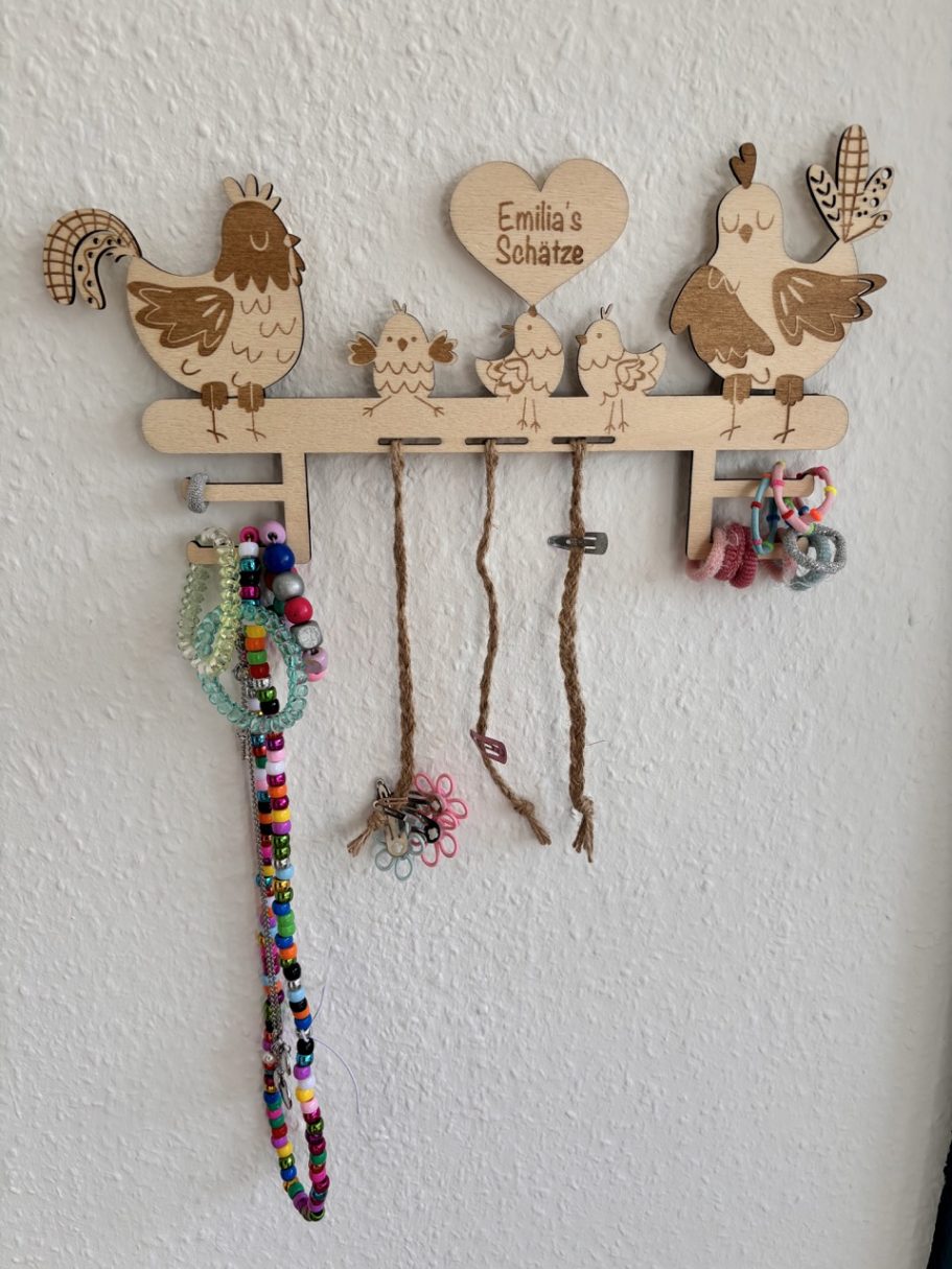 Holzhalter mit Hühner-Motiven und bunten Schnüren zum Aufhängen.